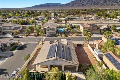 An aerial perspective reveals a well-maintained neighborhood with solar-equipped homes, nestled against a scenic mountain backdrop.