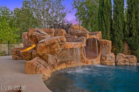 A rock waterfall feature and water slide create an inviting pool retreat.