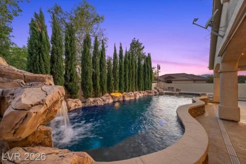An inviting pool with a rock waterfall and surrounding foliage creates a private outdoor sanctuary.