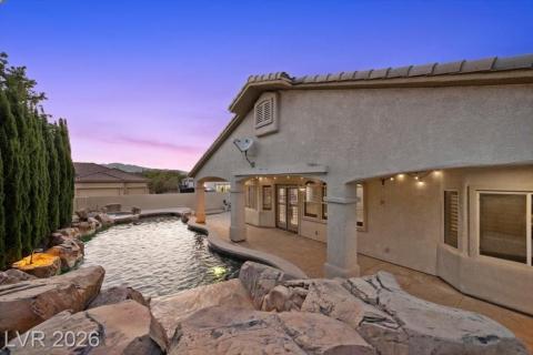 A captivating private backyard oasis awaits, featuring a custom rock-lined pool under a painted desert sky.
