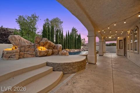 An inviting covered patio offers a refreshing pool with rock water features, creating an ideal outdoor retreat.