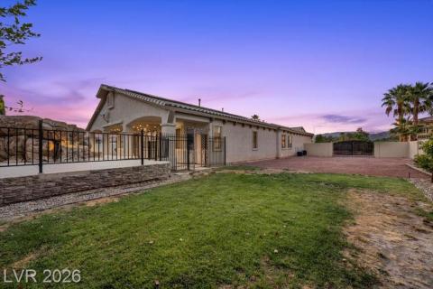 An inviting patio space and grassy yard offer prime outdoor living against a colorful evening sky.