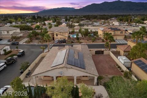 An aerial perspective reveals a charming residential street, complete with solar panels and a private pool, set against a mountainous desert landscape.