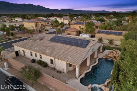 An aerial perspective reveals solar panels adorning the rooftop and a serene pool with a spa.