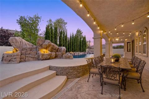 An inviting outdoor dining area overlooks a custom rock formation with waterfall and sparkling pool. An inviting outdoor dining area overlooks a custom rock formation with waterfall and sparkling pool.