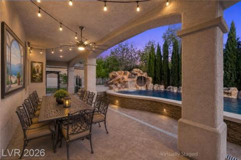 An inviting covered patio featuring a full dining setup and a refreshing pool with a rock waterfall. An inviting covered patio featuring a full dining setup and a refreshing pool with a rock waterfall.