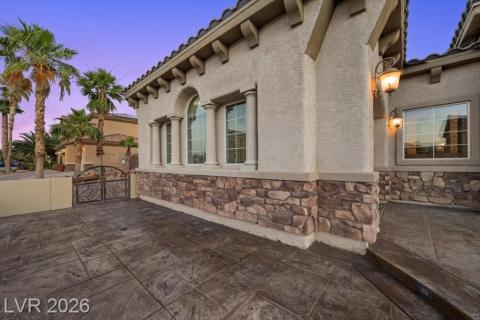 Ornate wrought iron gate opens to a private patio, flanked by classic stucco and stone architecture.