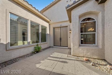A welcoming entry features decorative double doors and a patterned concrete pathway leading to the home's inviting facade.