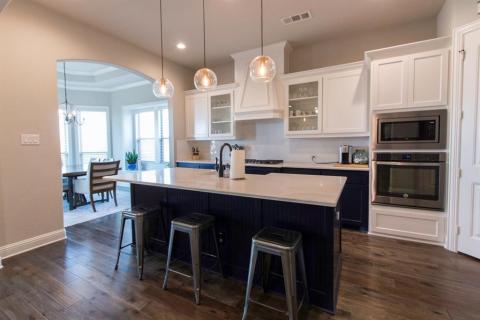 Breakfast bar topped with sparkling quartz counters has a farmhouse sink