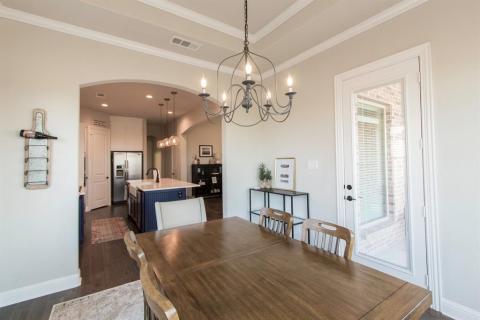Dining room has space for a large table and includes upscale light fixture. Door goes out to patio