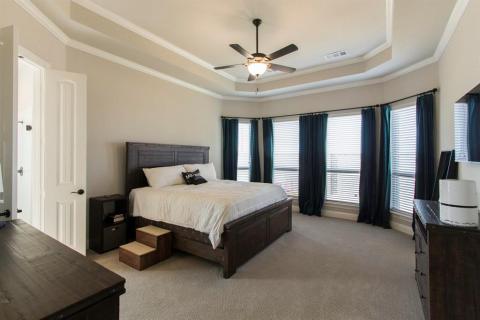 Master bedroom with tray ceiling and crown molding. Bay windows looking to backyard