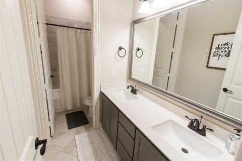 Hall bath has double sink with door to separate shower area