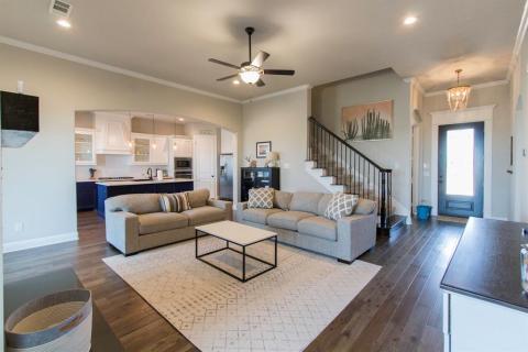View of front door, beautiful wood floors, open living/kitchen. Stairs with wrought iron railing lead up to the gameroom