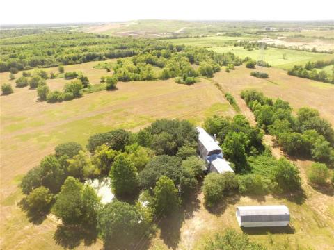 Drone photo of dwelling, metal storage building, and pond.